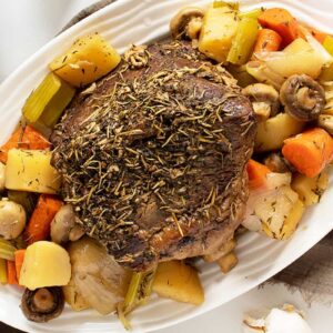 cross rib roast on a white platter with vegetables
