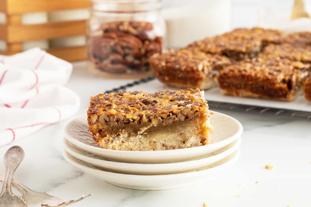 pecan pie bars on a stack of white plates