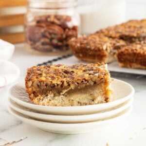 pecan pie bars on a stack of white plates