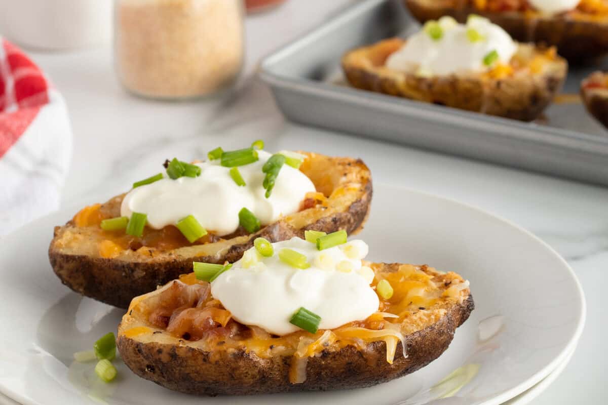 potato skins on a white plate with sour cream and chives