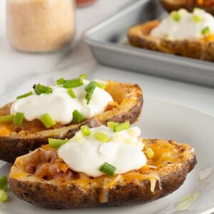 potato skins on a white plate with sour cream and chives