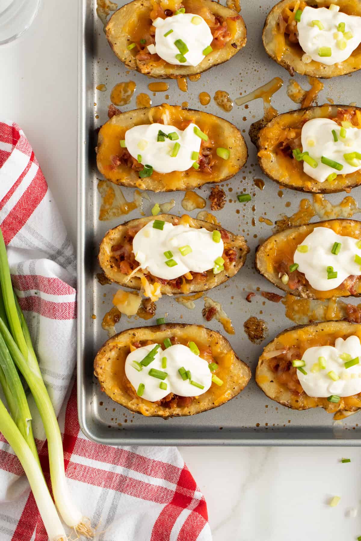 potato skins on a baking pan topped with sour cream and chives