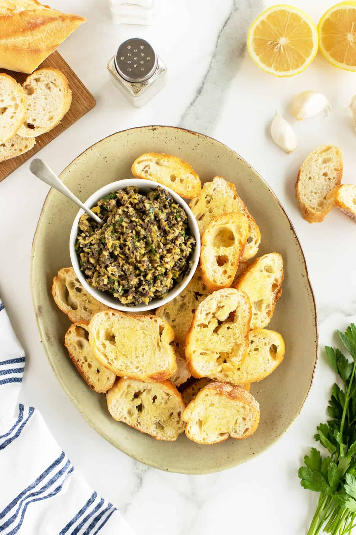 tapenade in a bowl surrounded by slices of toasted baguette