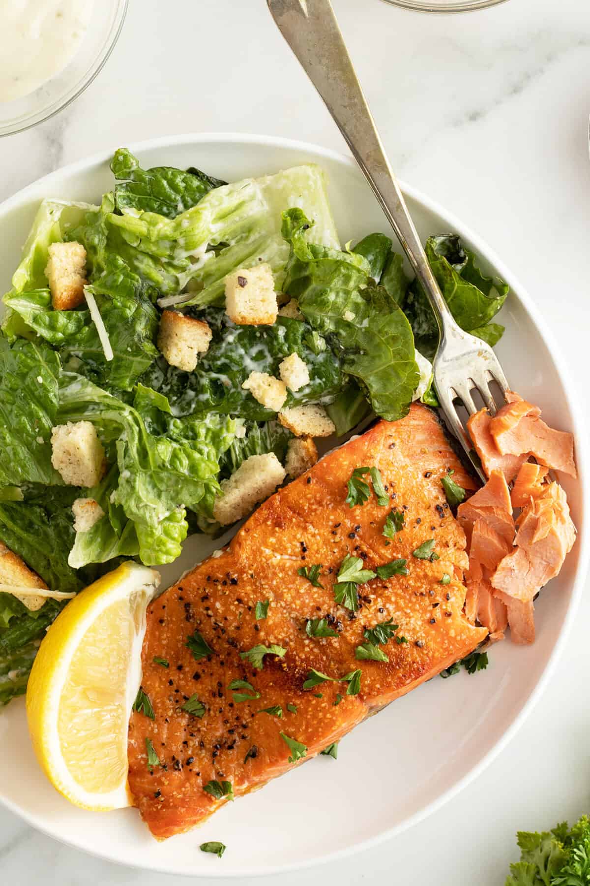 Air fryer salmon on a white plate with a caesar salad