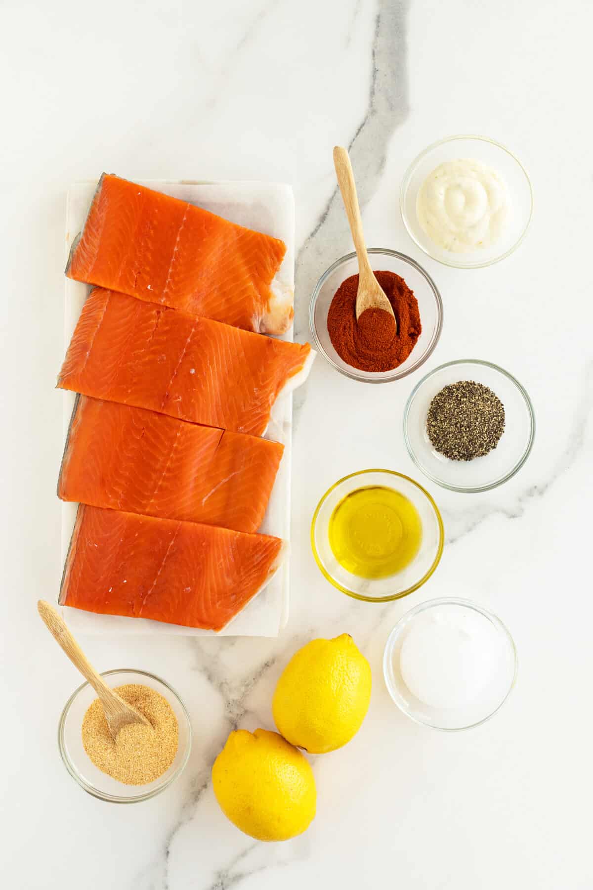 Air fryer salmon ingredients in small clear bowls beside salmon fillets