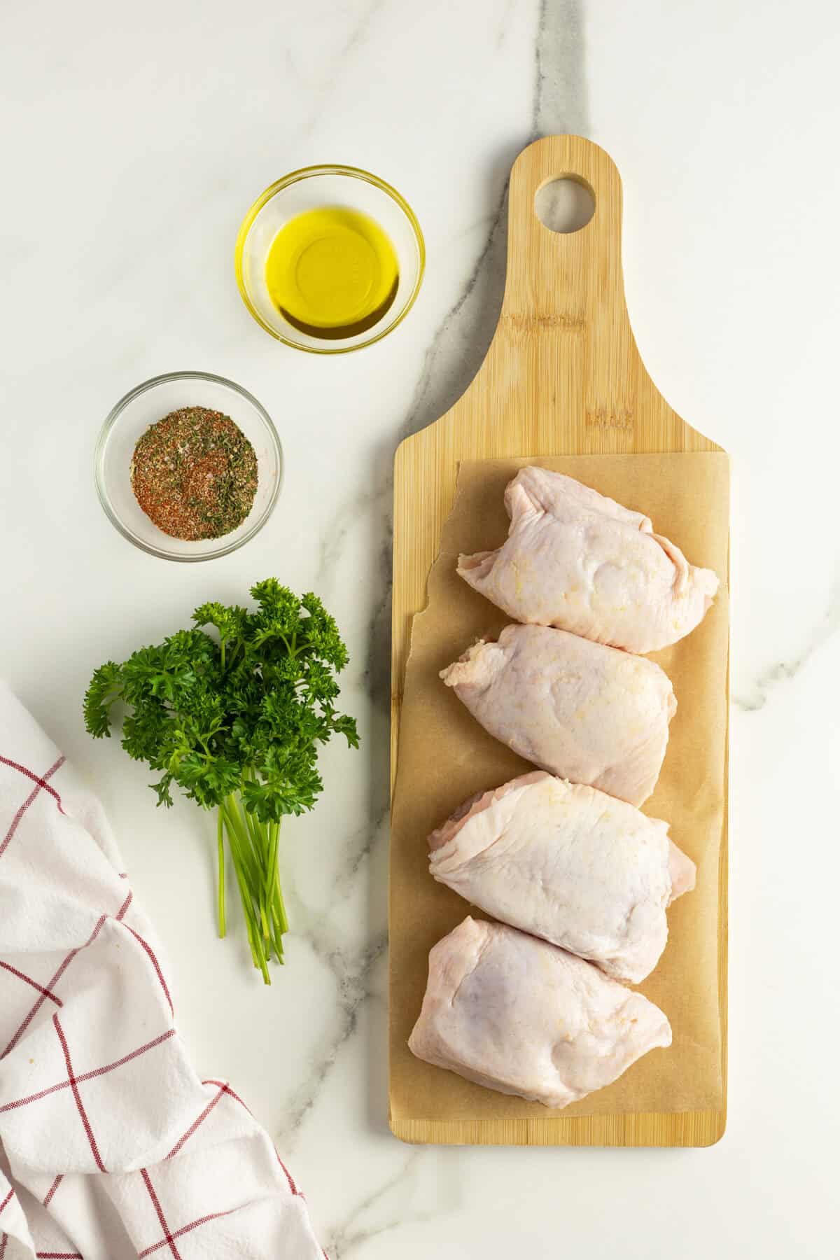 Air fryer chicken thighs ingredients on a wooden cutting board