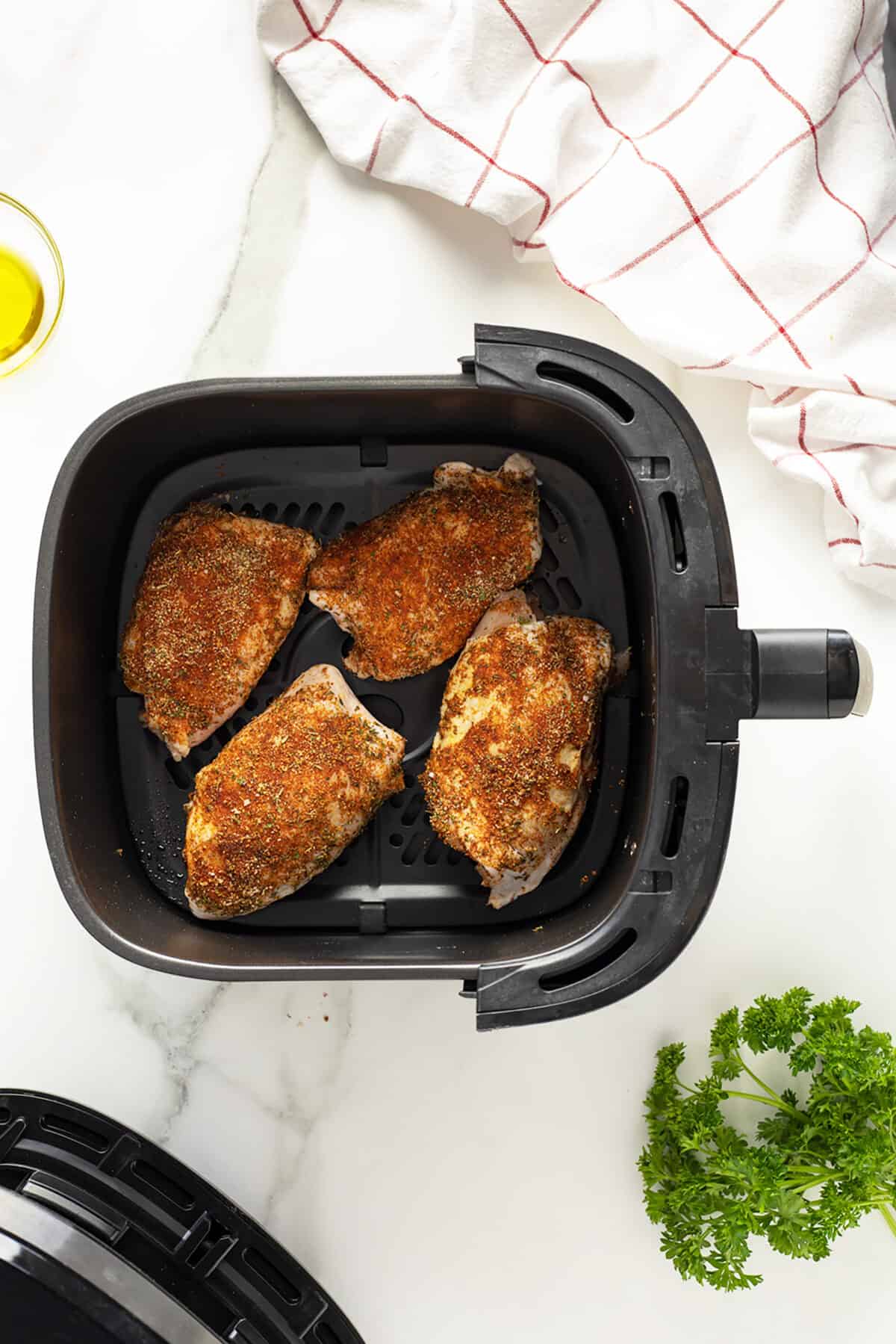 Air fryer chicken thighs seasoned and in the air fryer basket
