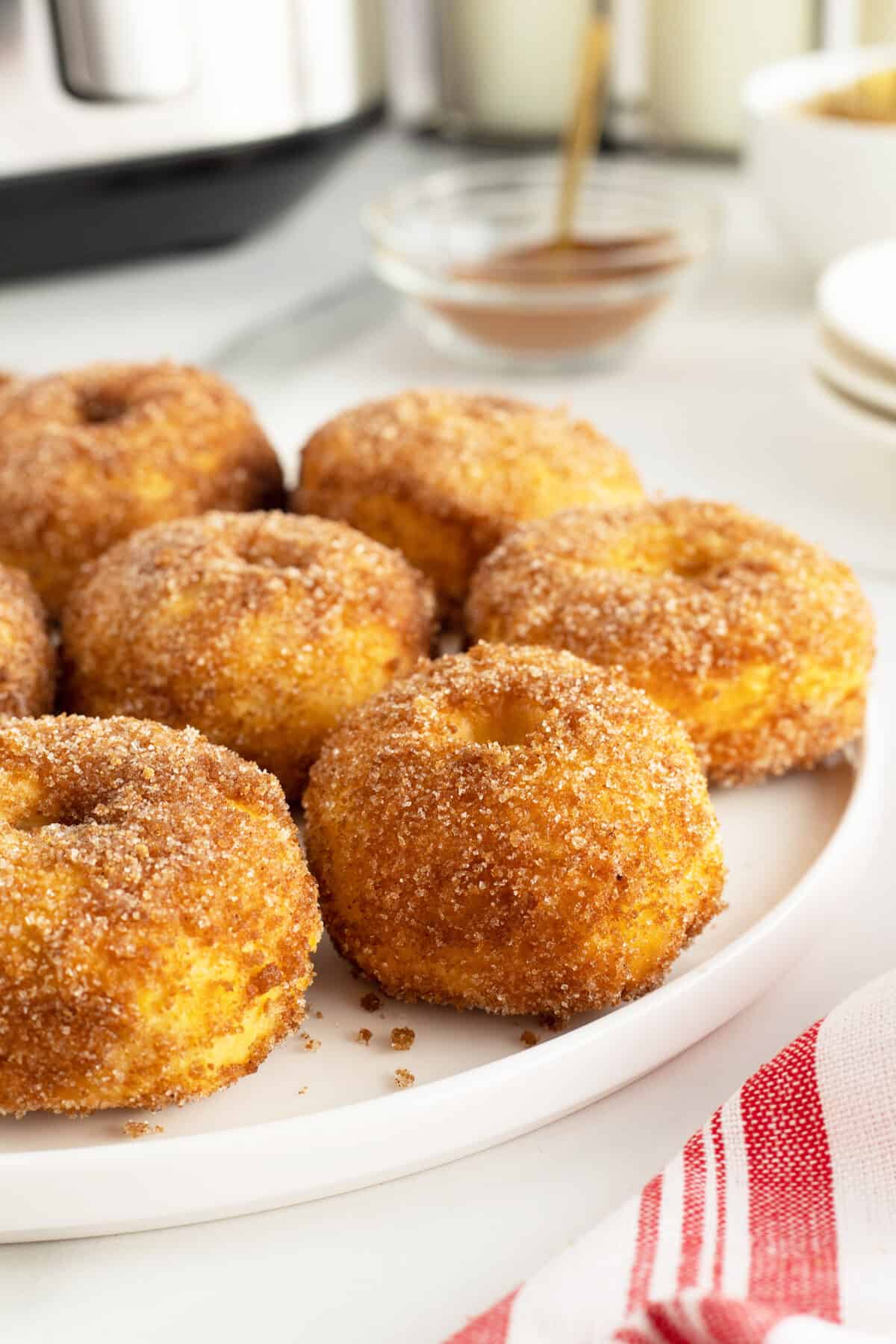 air fryer doughnuts on a plate with sugar and cinnamon
