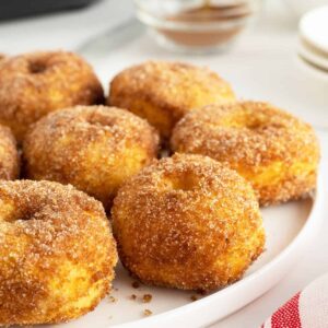 air fryer doughnuts on a plate with sugar and cinnamon