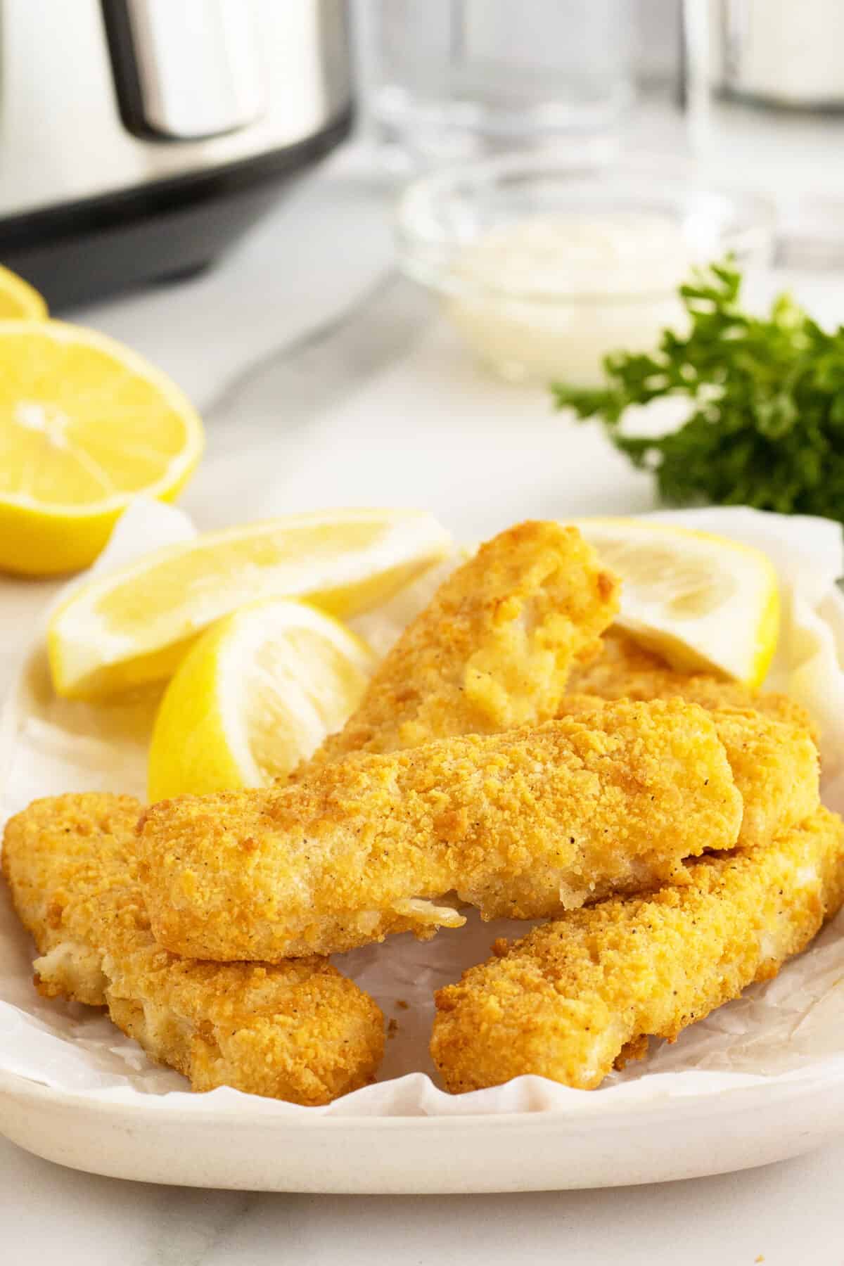 air fryer fish sticks piled on a white plate