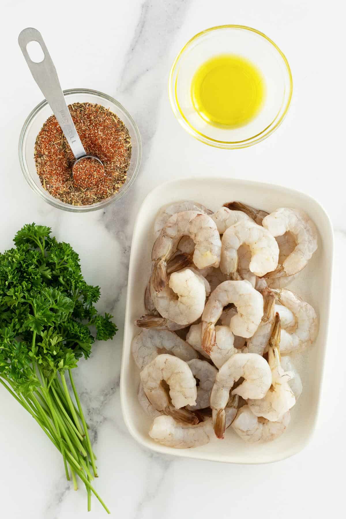 Air fryer shrimp raw on a platter with ingredients around it