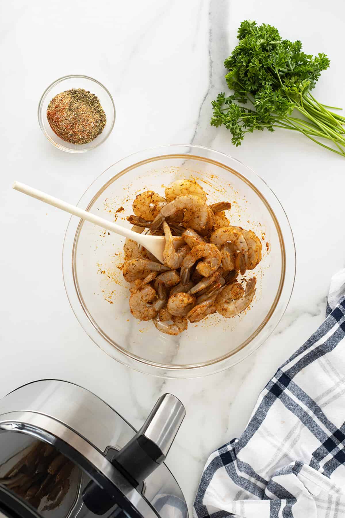 Air fryer shrimp raw in a bixing bowl with spices