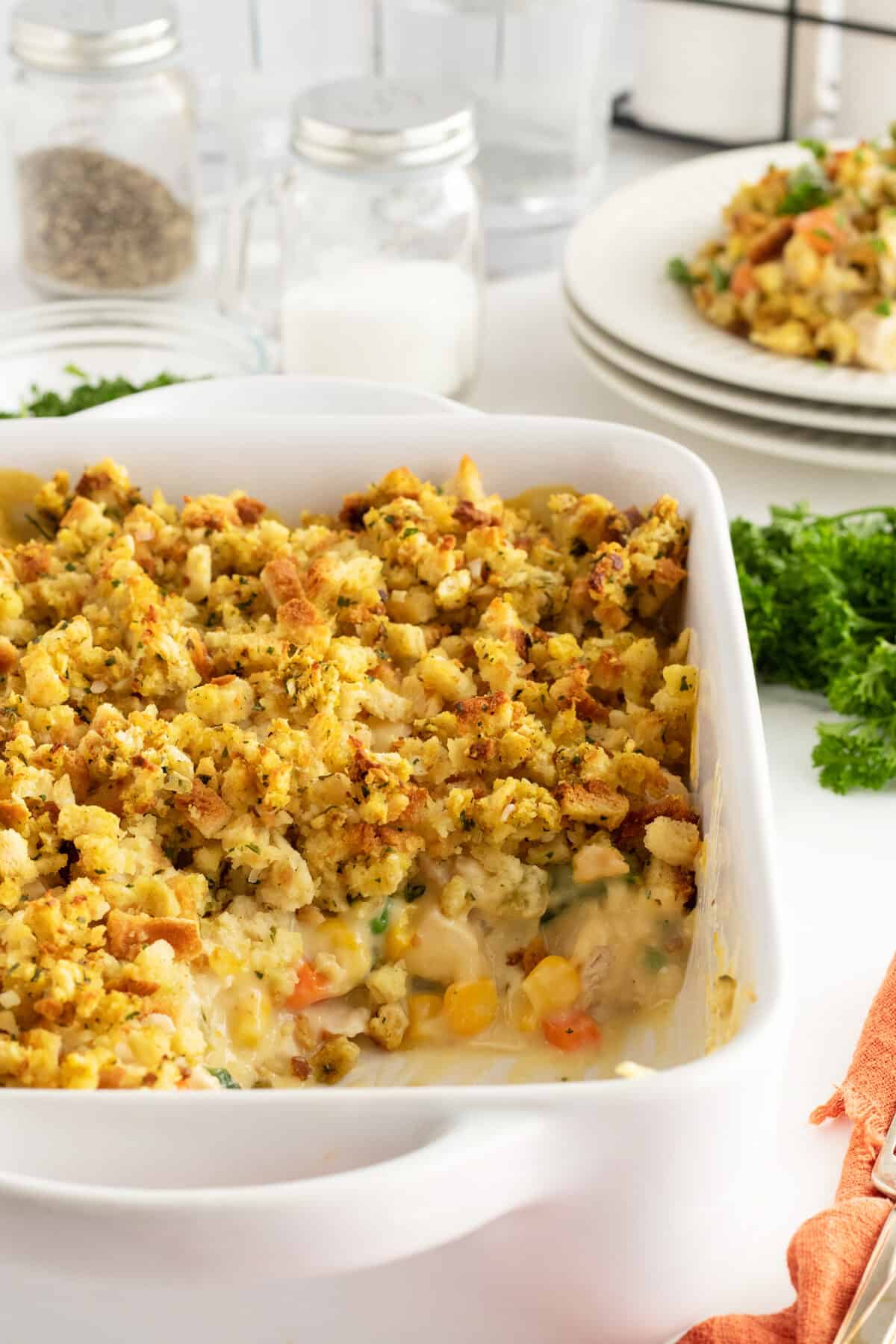 Chicken and stuffing casserole in a white baking dish closeup with a slice missing