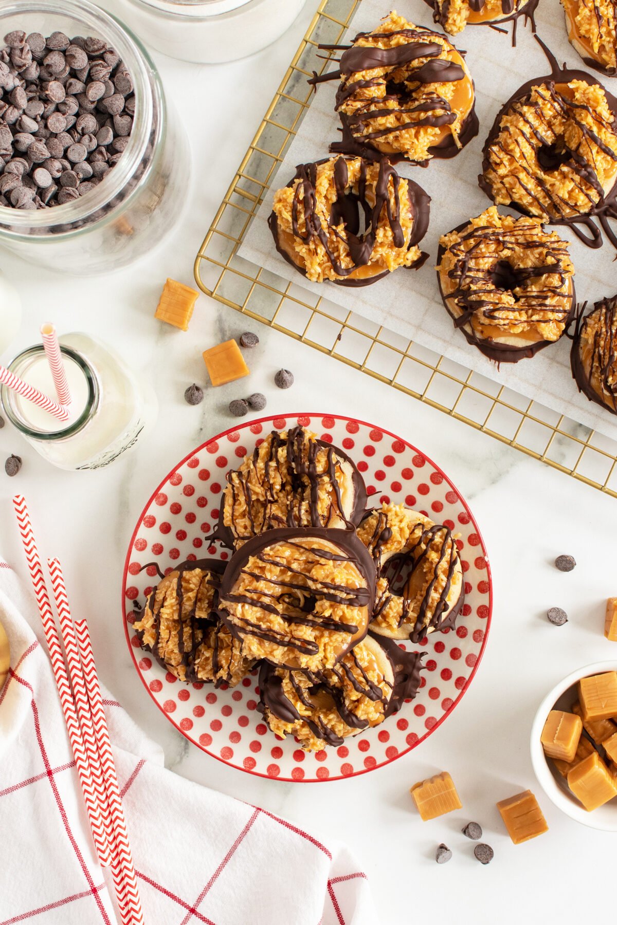 samoa cookies piled on a plate with some on a baking tray