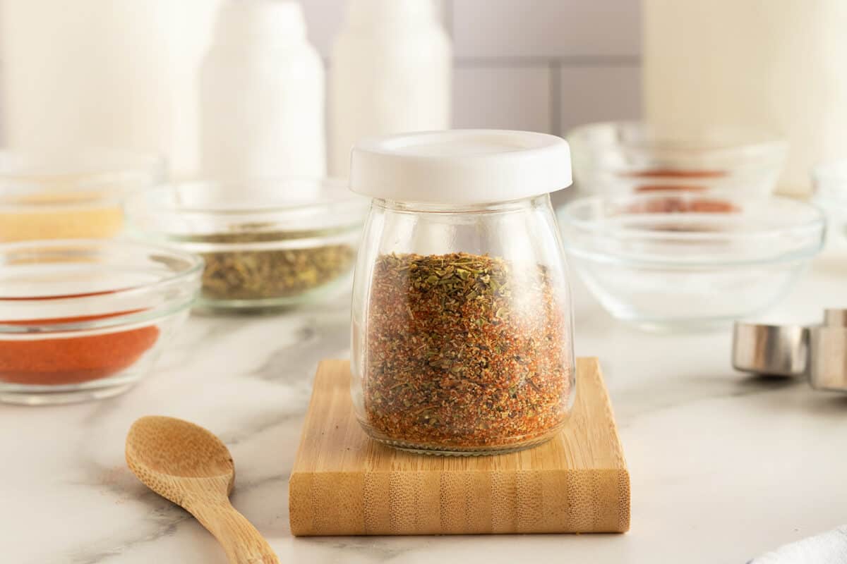 shrimp seasoning in a small tapered clear glass jar on a cutting board