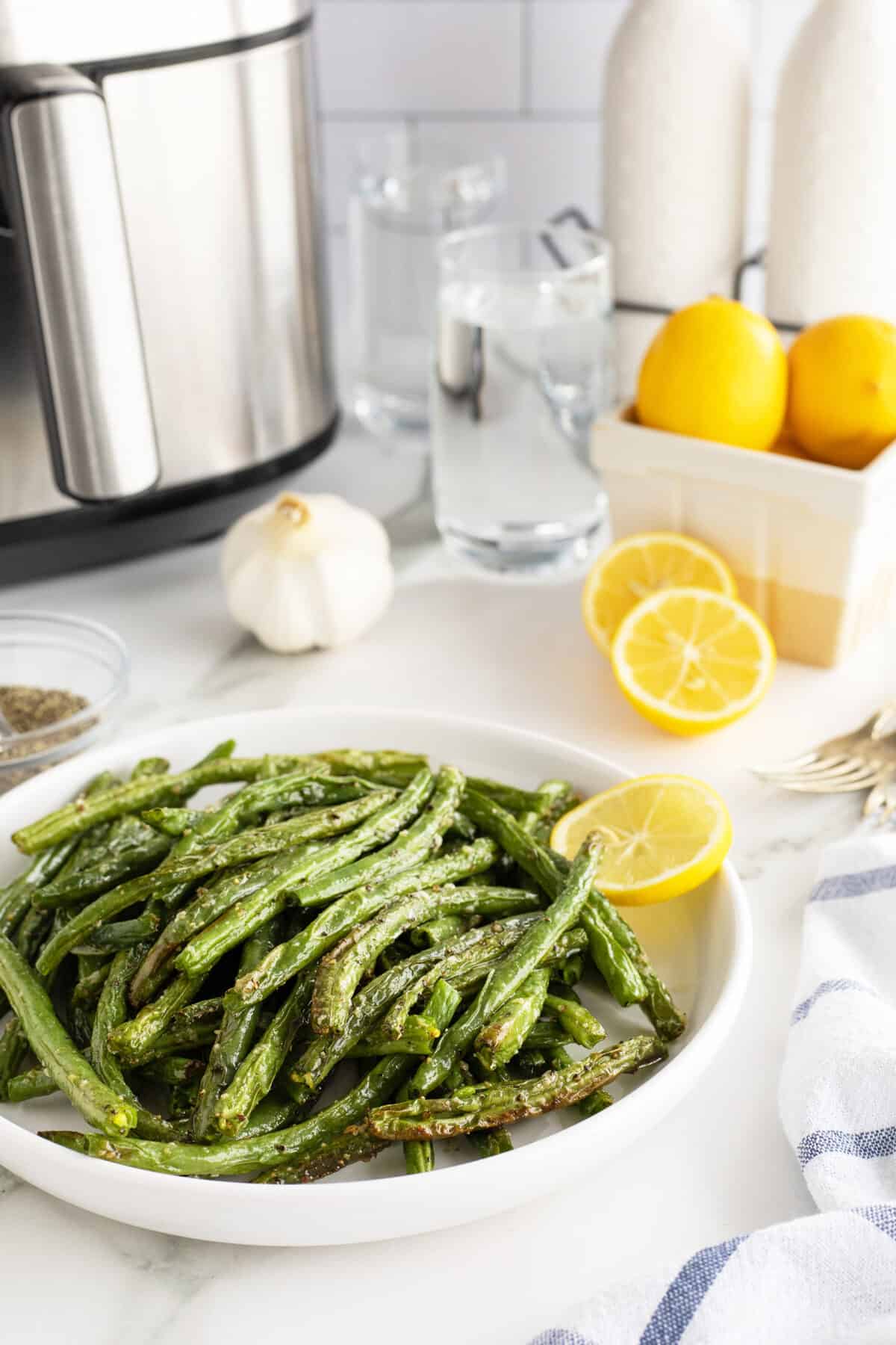 air fryer green beans on a white plate with the air fryer behind it