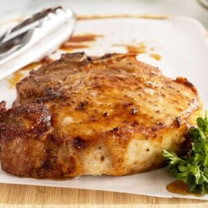 air fryer pork chop on a piece of parchment paper on a cutting board