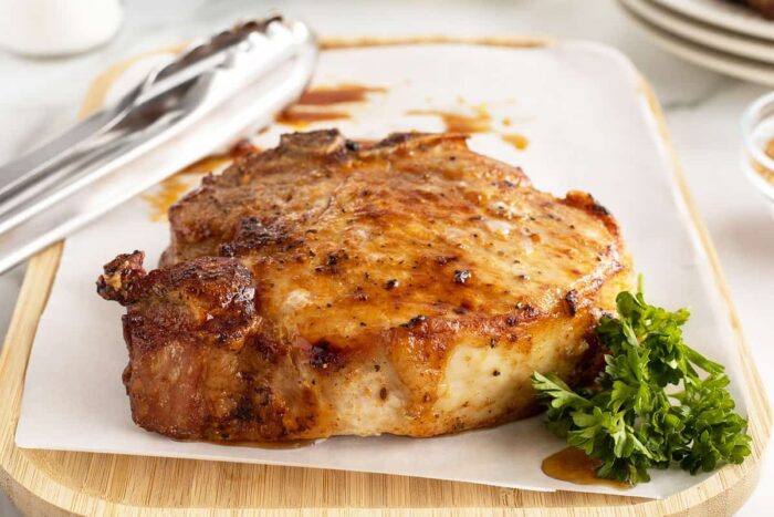 air fryer pork chop on a piece of parchment paper on a cutting board