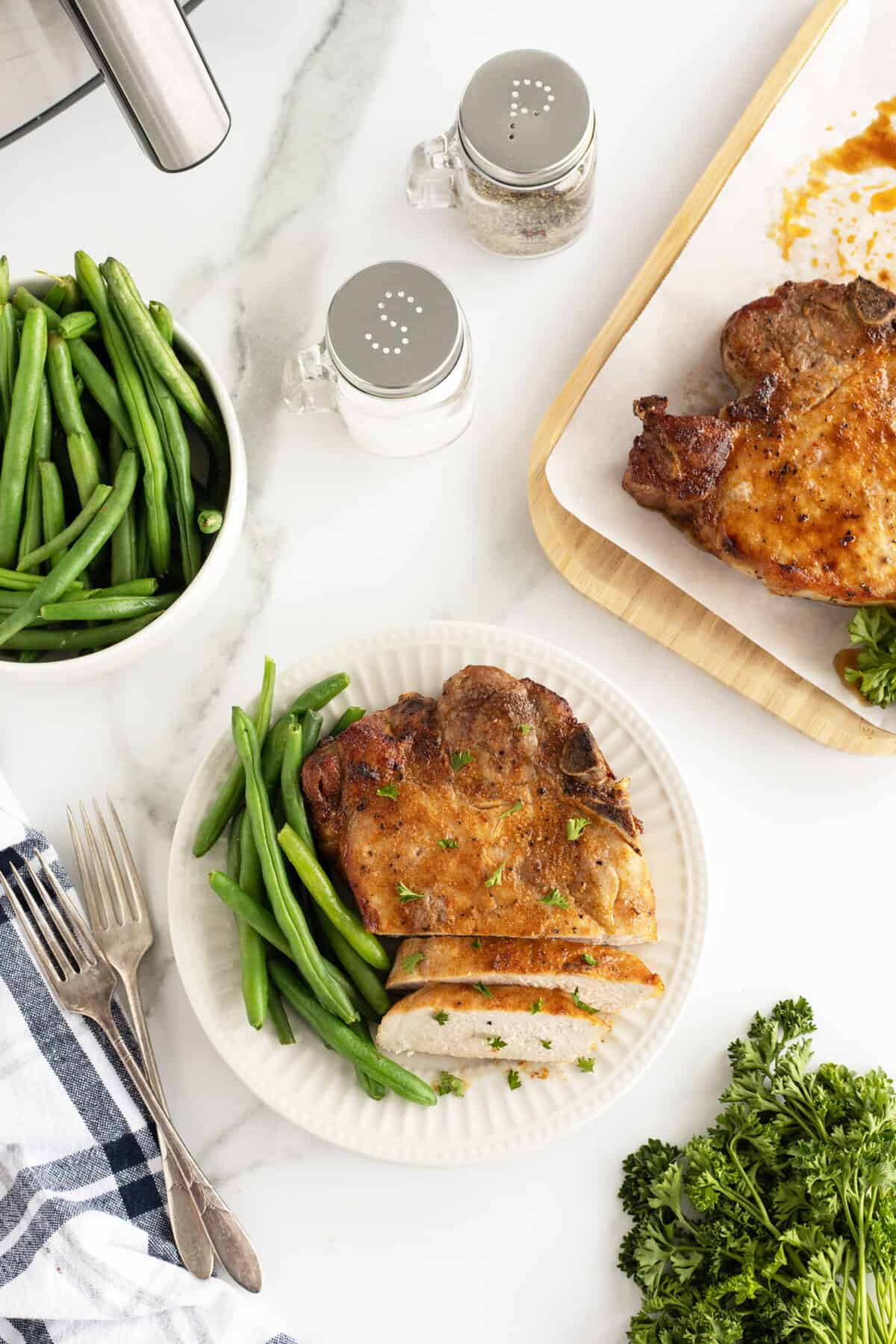 air fryer pork chops on a whit plates with green beans