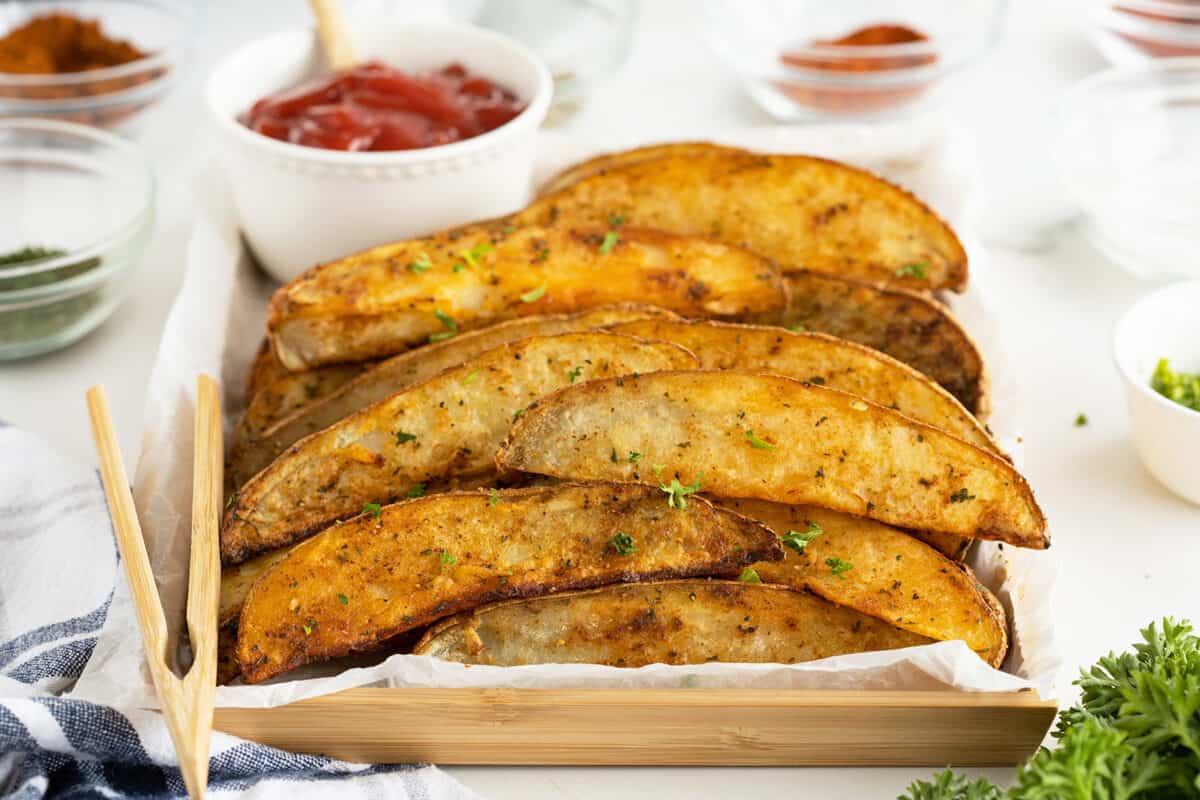 air fryer potato wedges on parchment paper in a dish