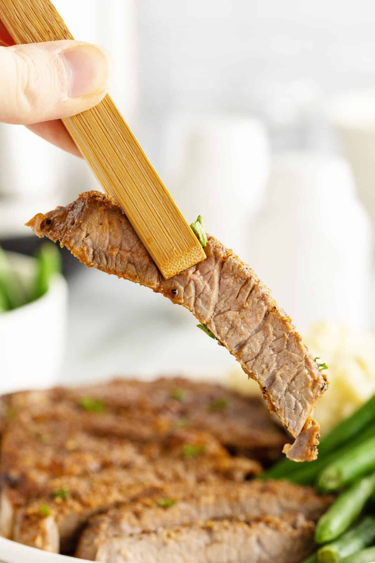 air fryer steak slice inbetween wooden tongs