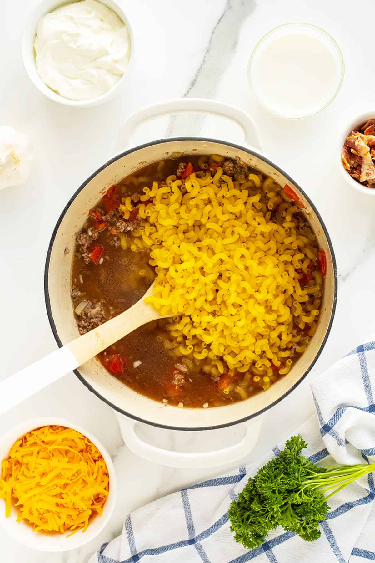 cheeseburger casserole in a pot with the dry macaroni added on top