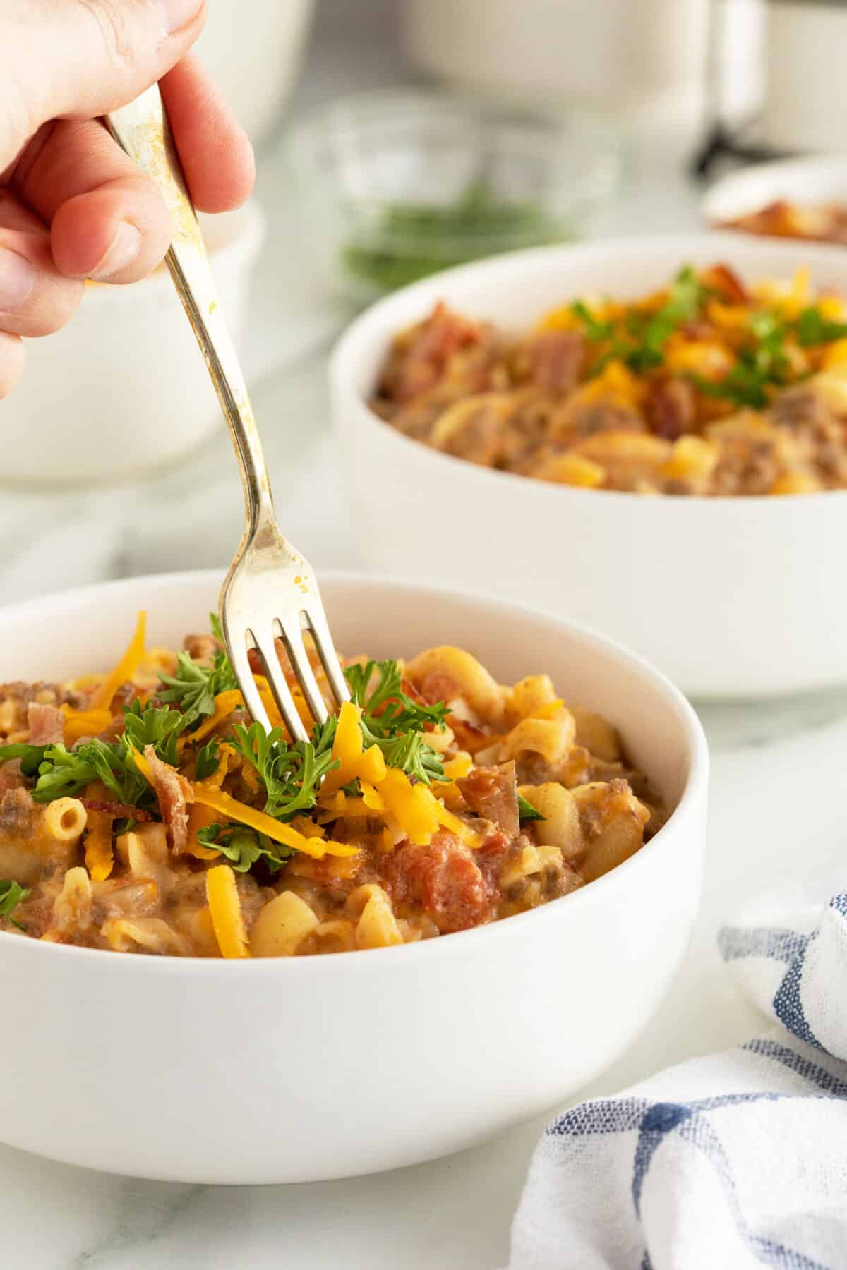 cheeseburger casserole in a white bowl with a fork in the bowl