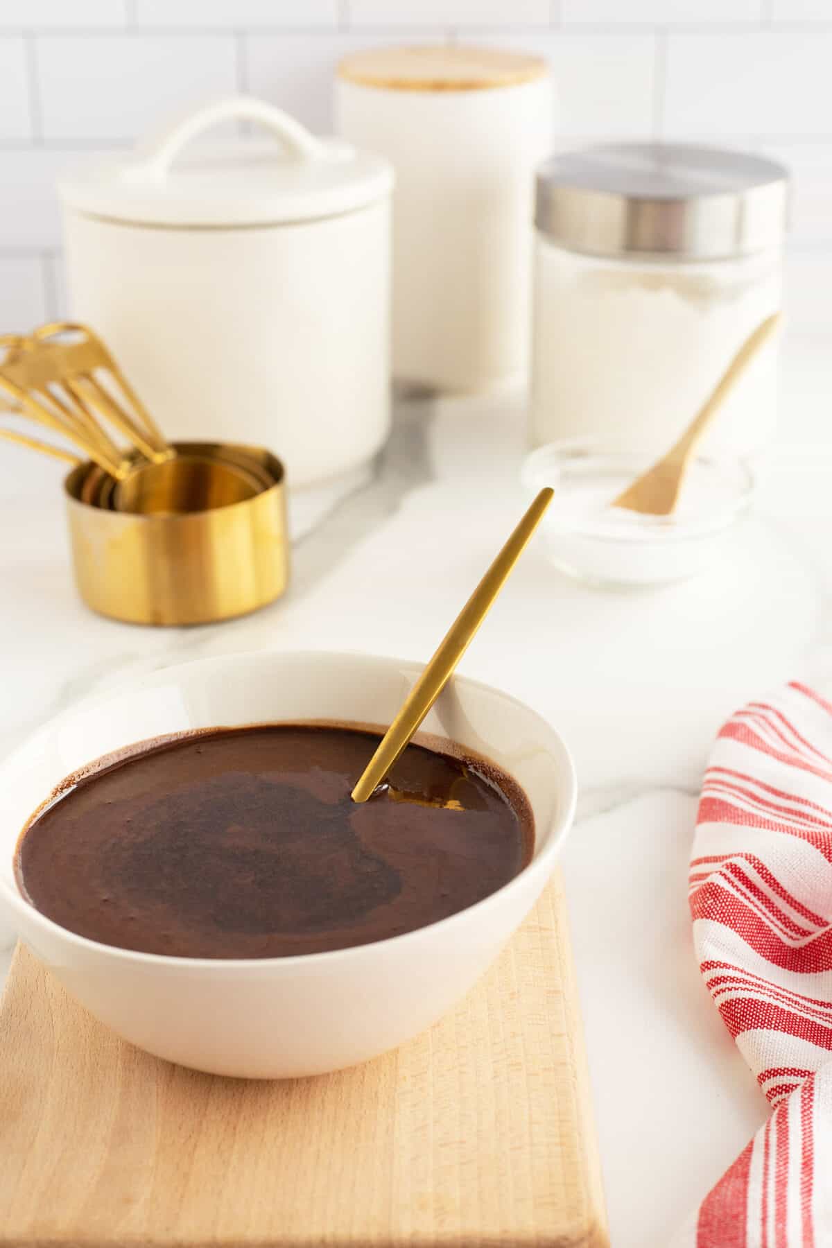 chocolate sauce in a white bowl with a brass spoon