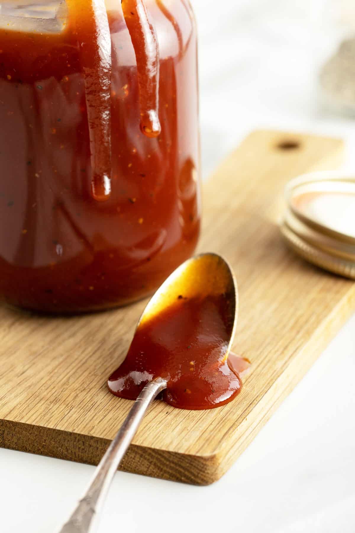 Homemade BBQ Sauce  on a spoon overflowed onto a cutting board