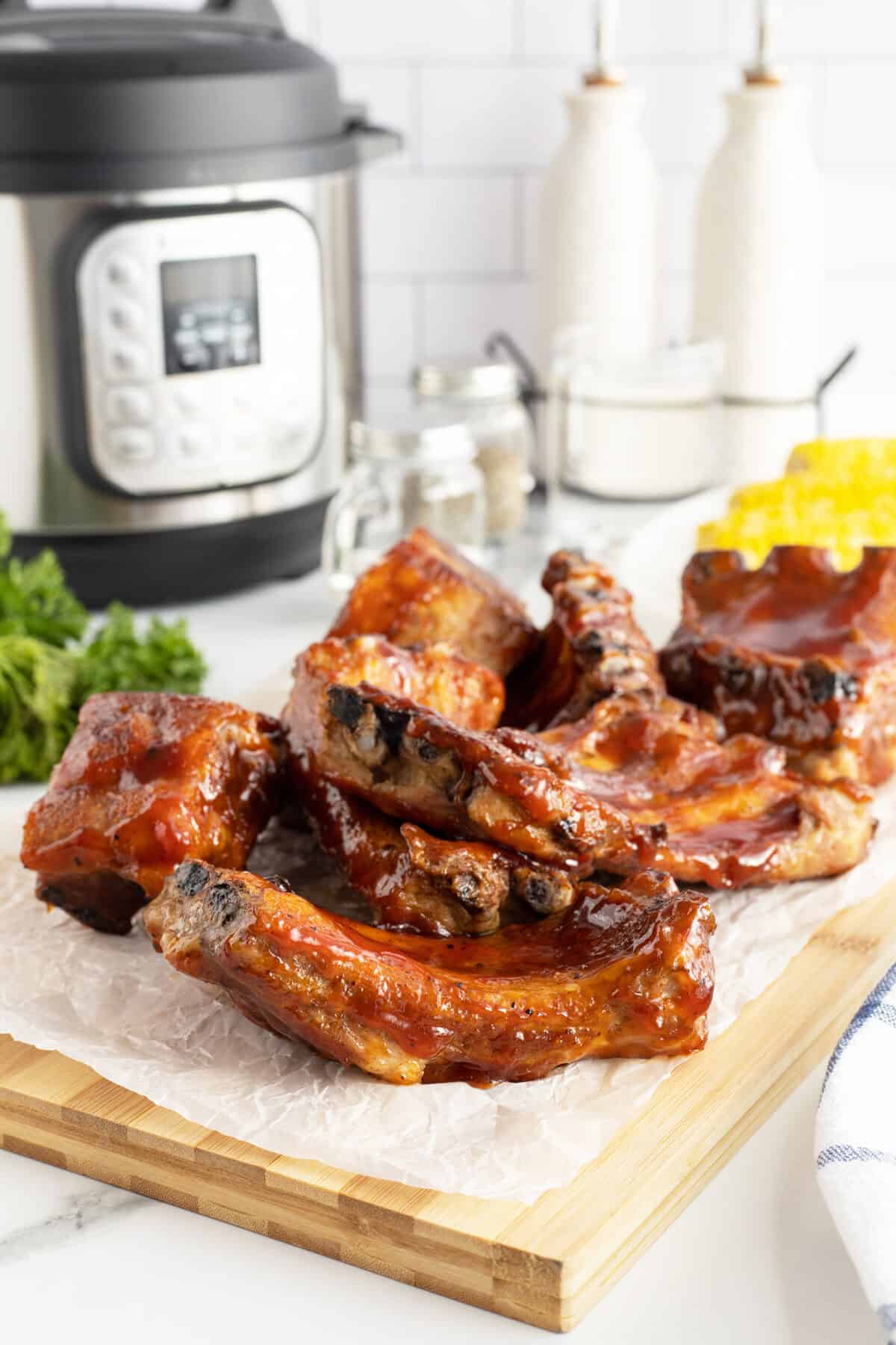 instant pot ribs  on a cutting board with the instant pot behind