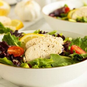 poached chicken in a bowl on a bed of lettuce and tomatoes