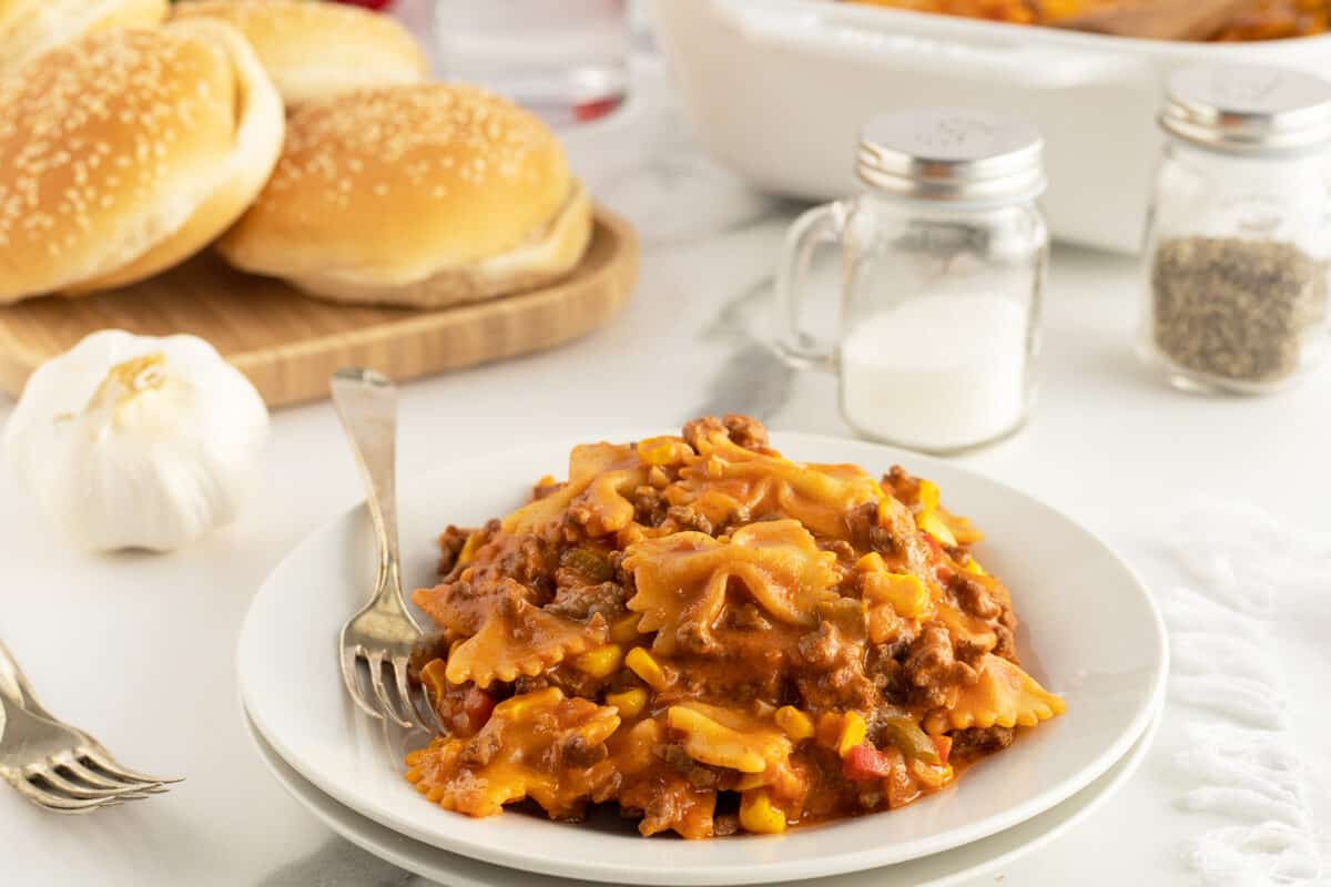 sloppy joe casserole on a white plate with buns stacked behind it