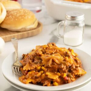 sloppy joe casserole on a white plate with buns stacked behind it