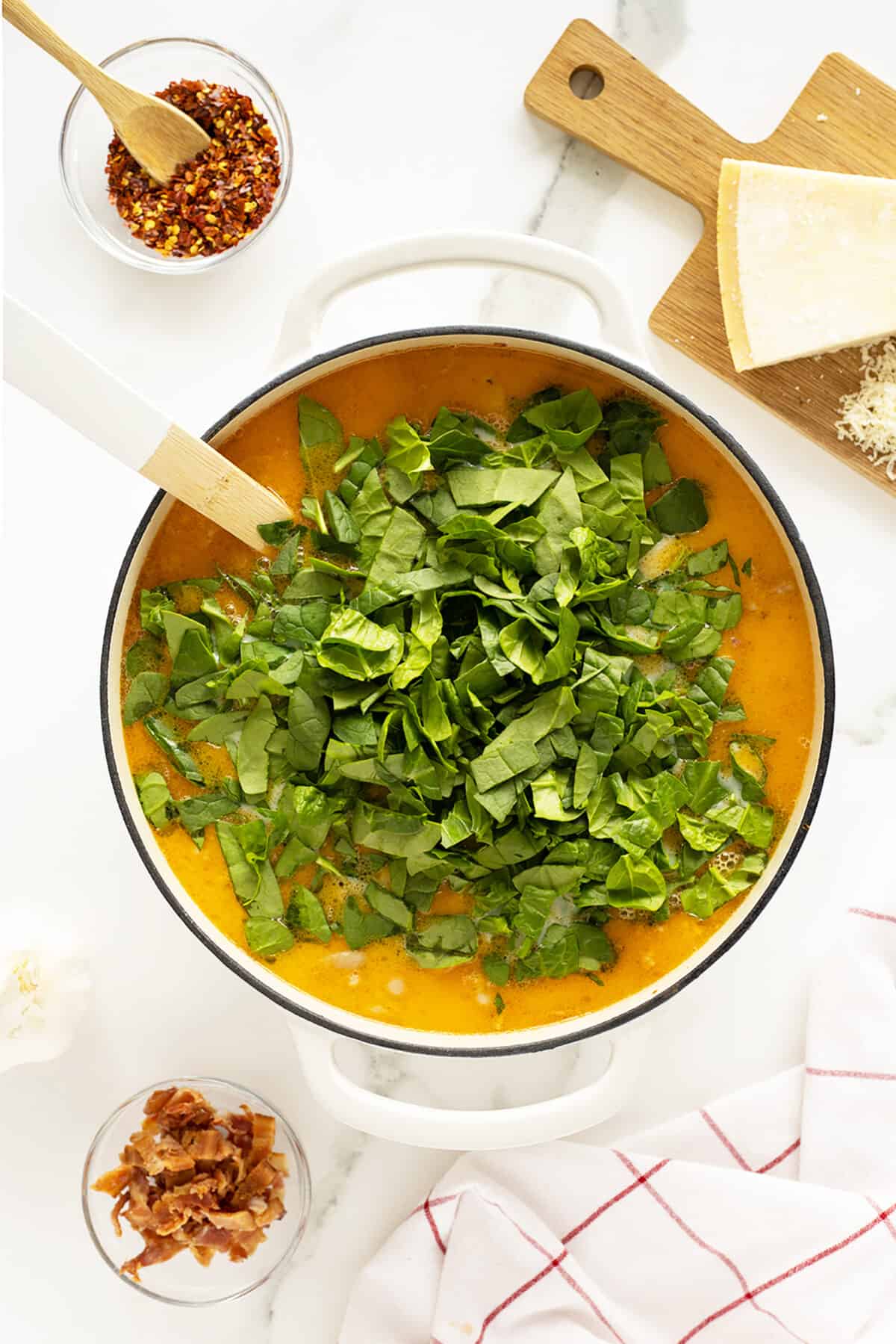 zuppa toscana in a pot with fresh spinach on top