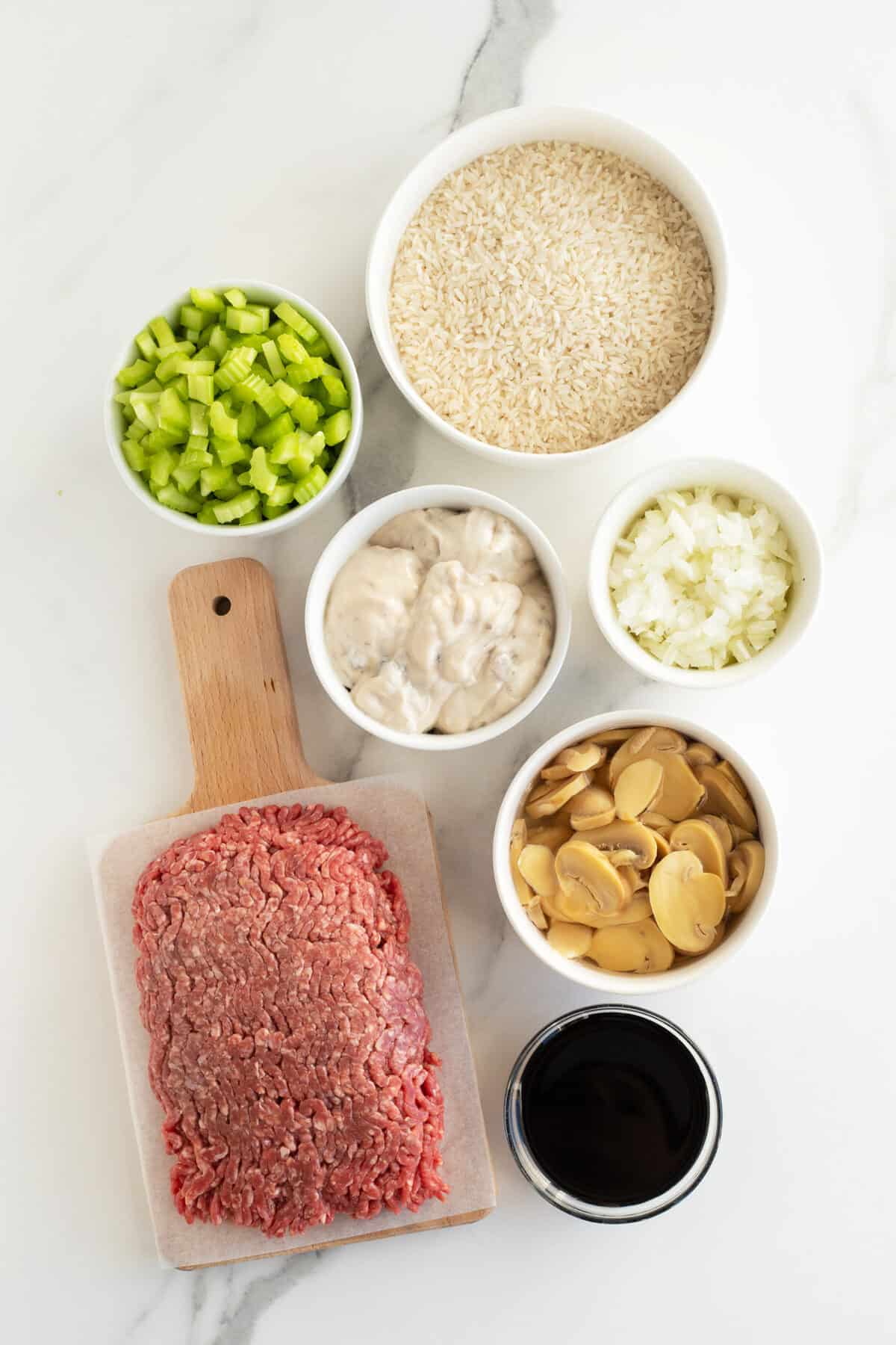 ground beef and rice ingredients in small clear bowls and a cuttingboard with raw beef