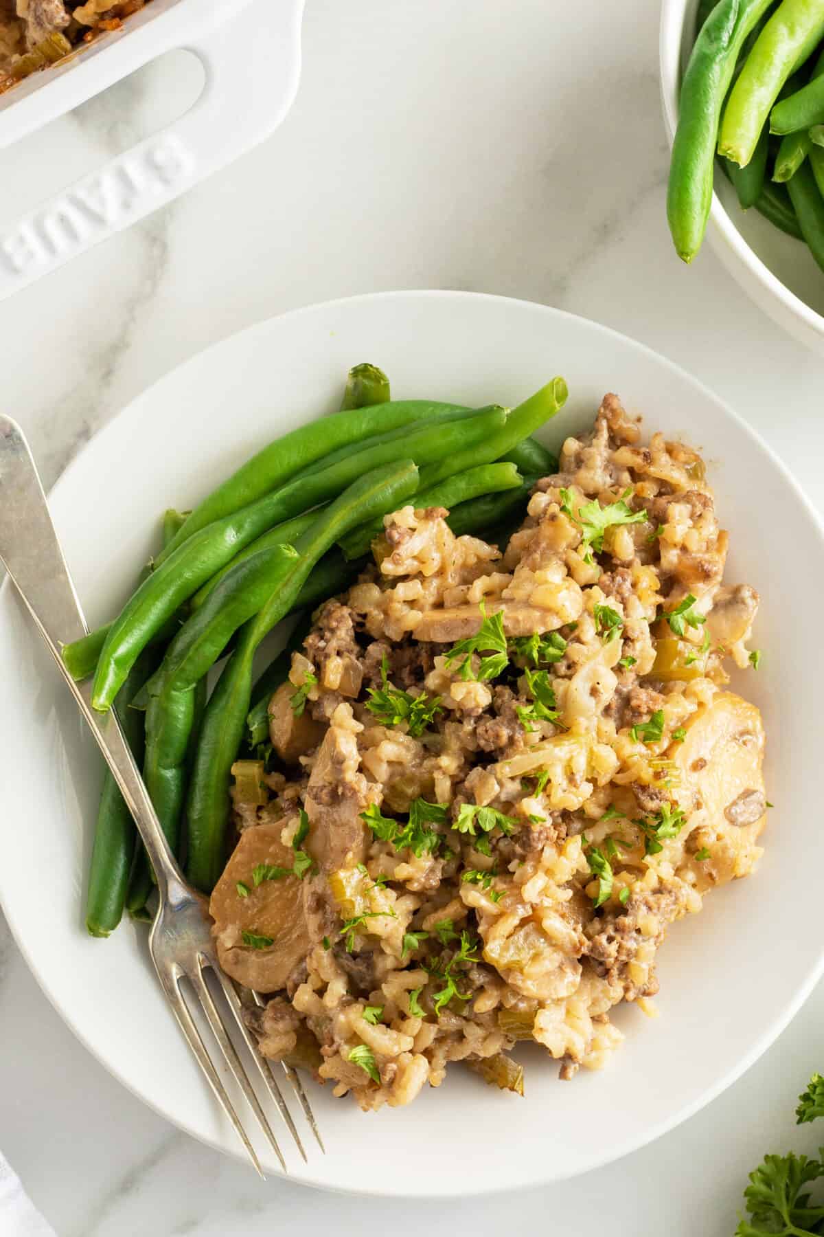 ground beef and rice overhead view on a white plate with green beans