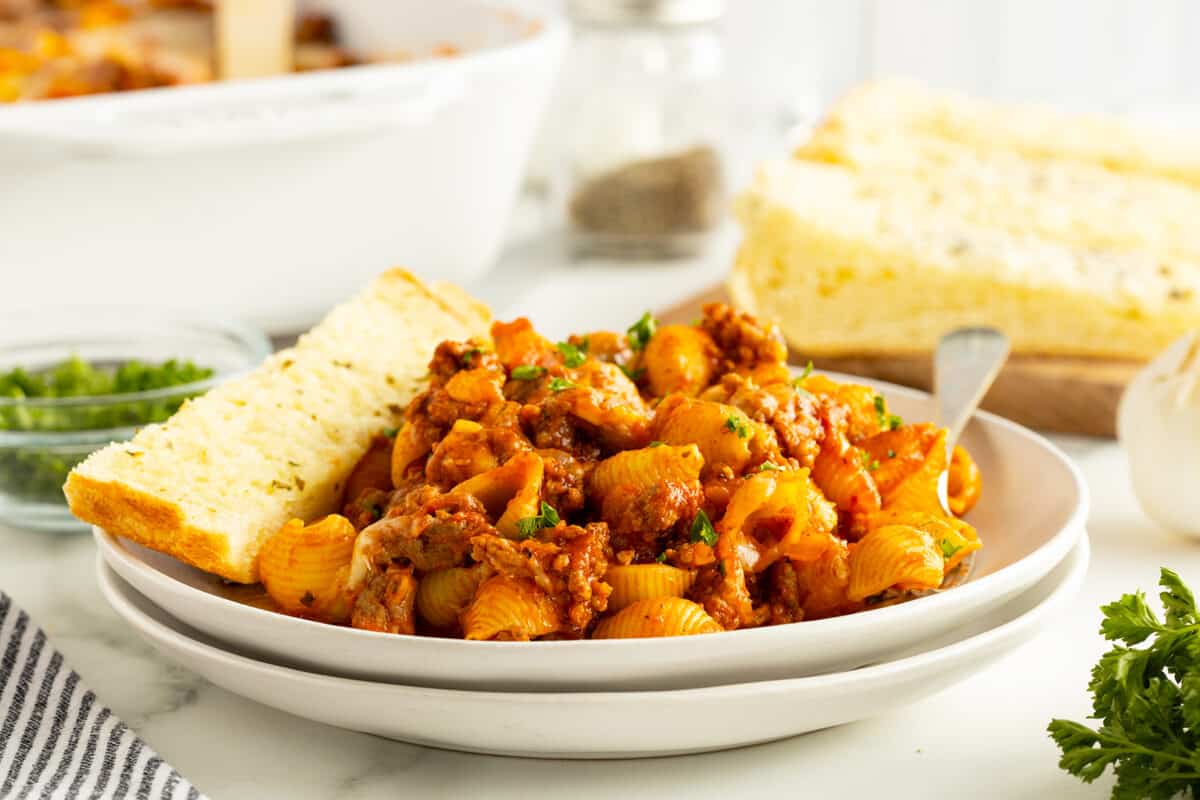 pasta bake on a whitew plate with a piece of garlic bread