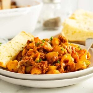 pasta bake on a whitew plate with a piece of garlic bread