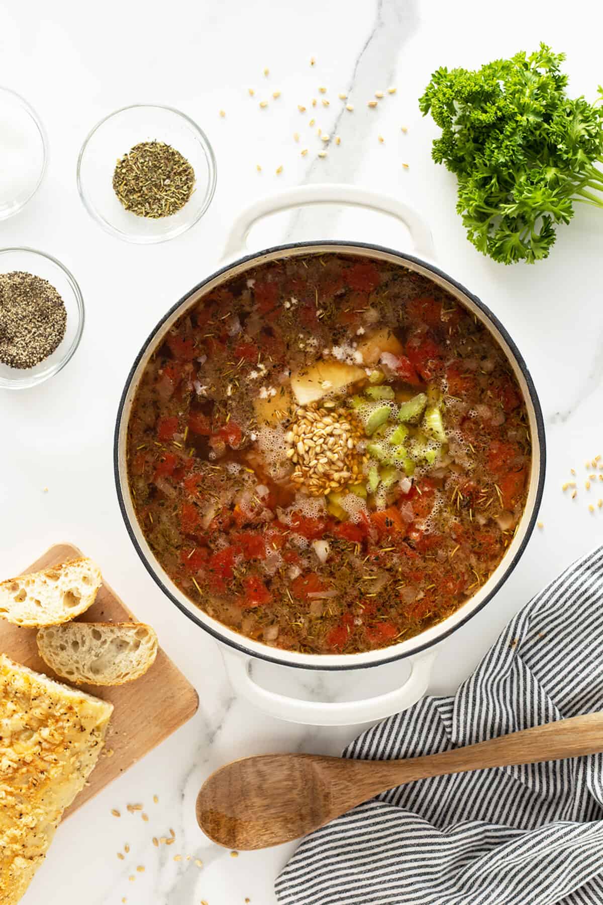 beef barley soup in a pot with ingredients added on top