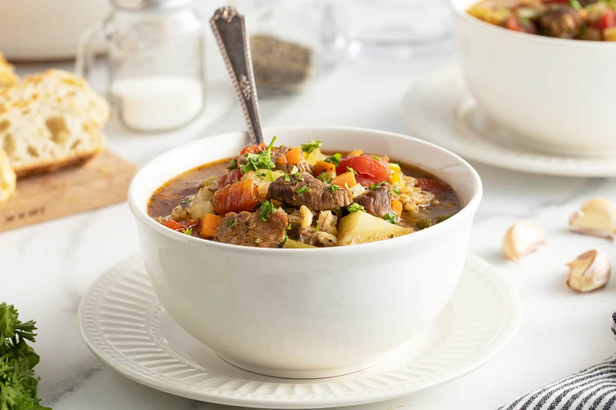 beef barley soup in a white bowl with a spoon
