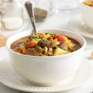 beef barley soup in a white bowl with a spoon