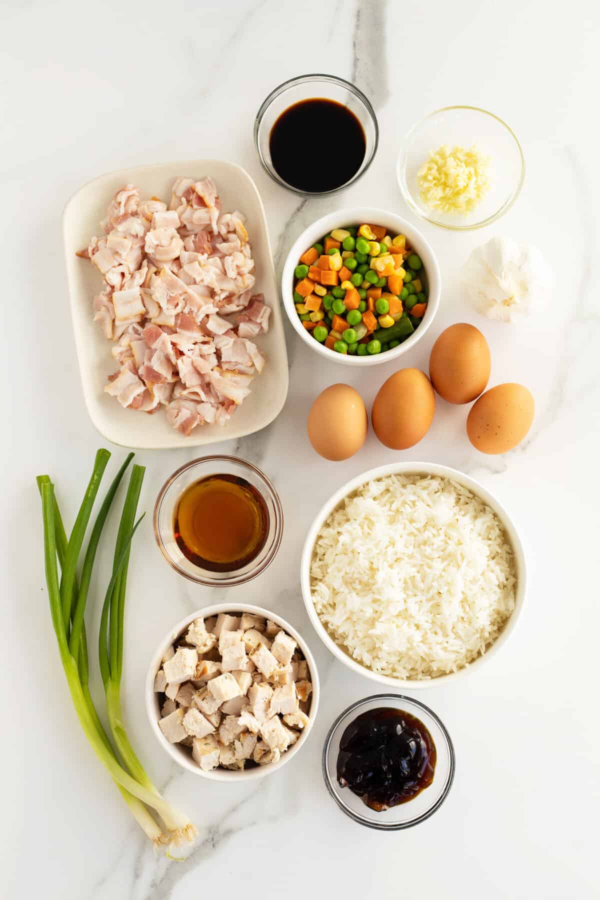 chicken fried rice ingredients in small white bowls and a bunch of green onions
