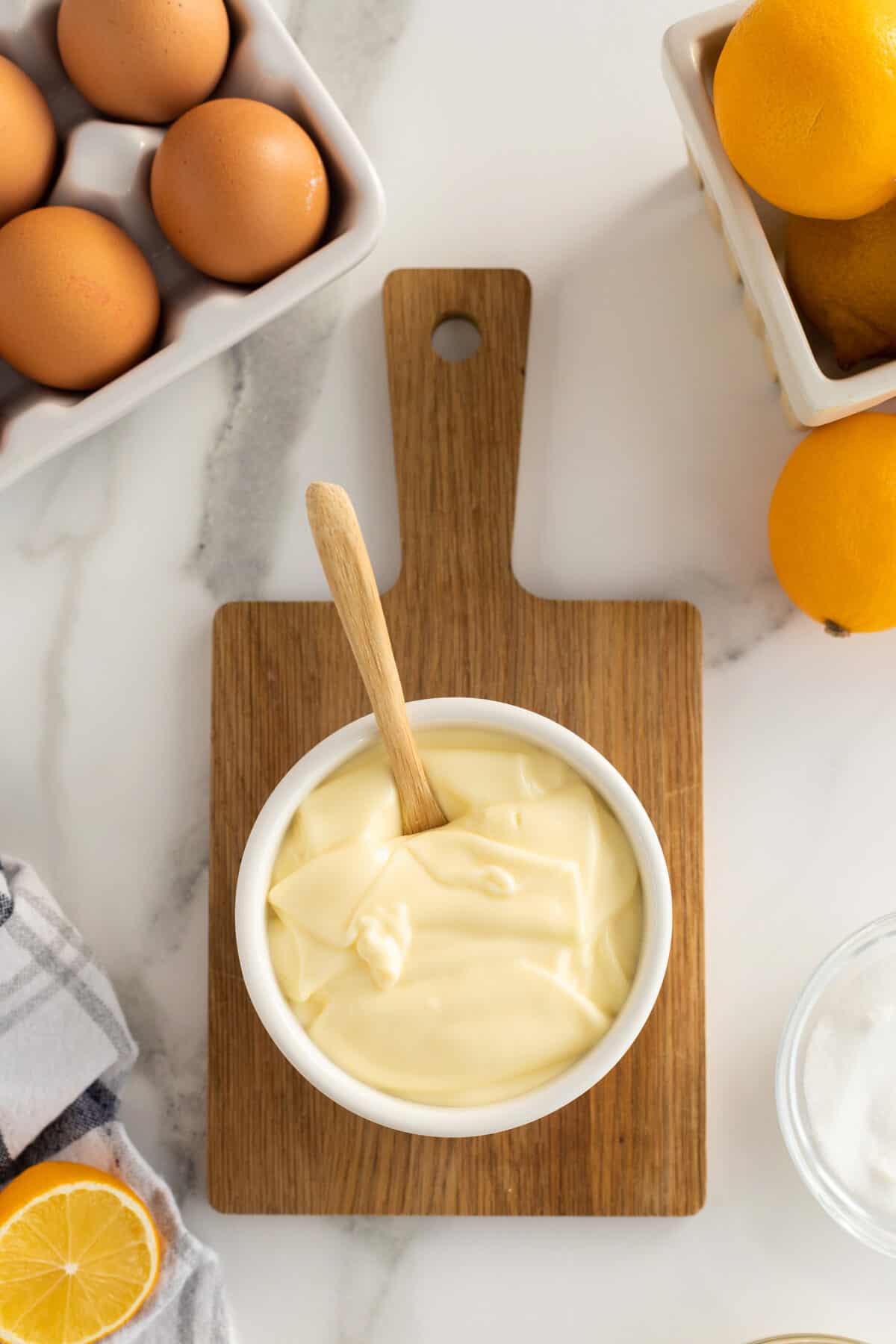 homemade mayonnaise  in a white bowl on a brown wooden cutting board