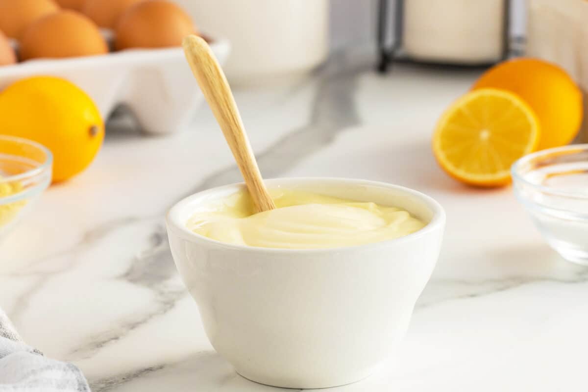 homemade mayonnaise  in a white bowl with a wooden spoon in it