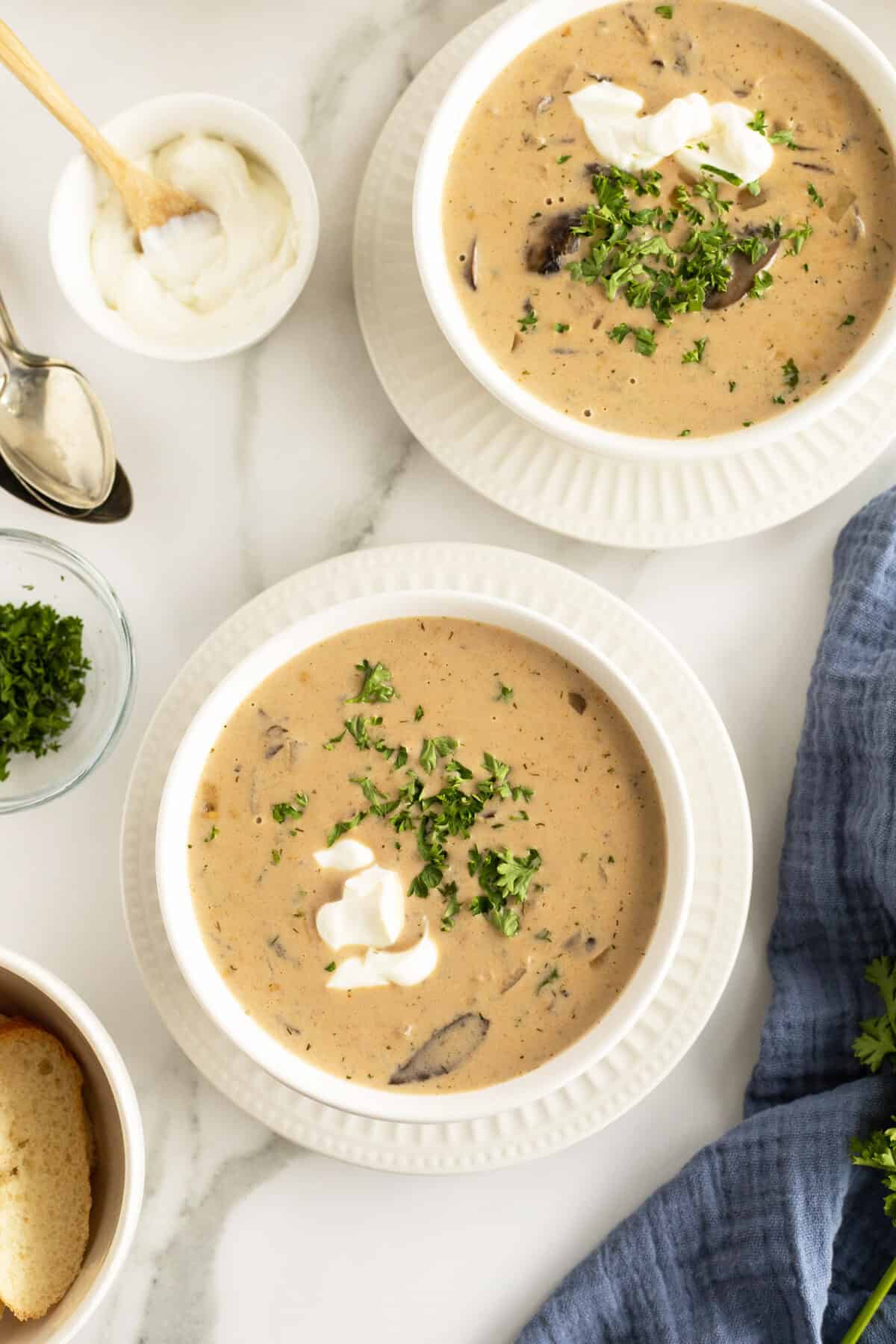 hungarian mushroom soup in two white bowls with a bit of cream and parsley on top