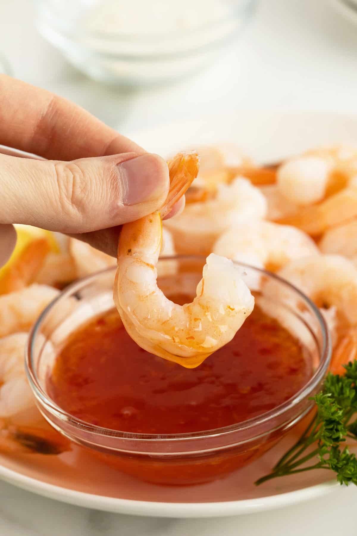 poached shrimp held up and dipped in hot chili sauce