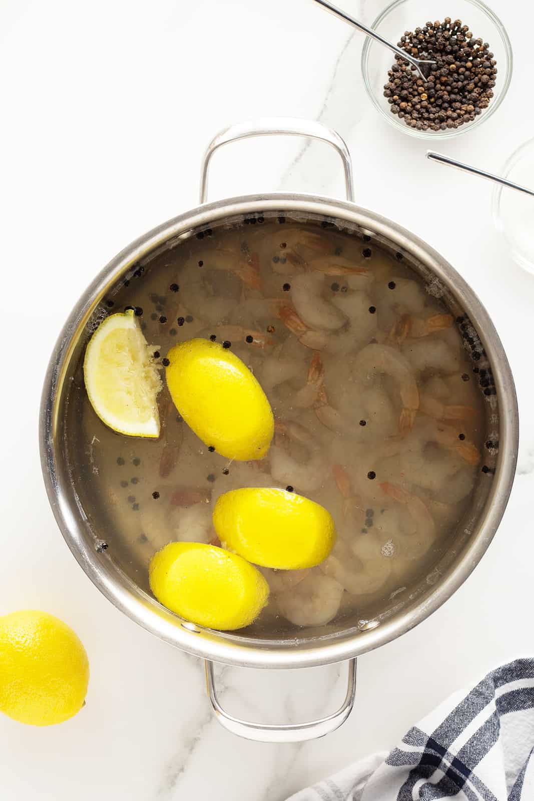 poached shrimp in a pot with floating lemon wedges