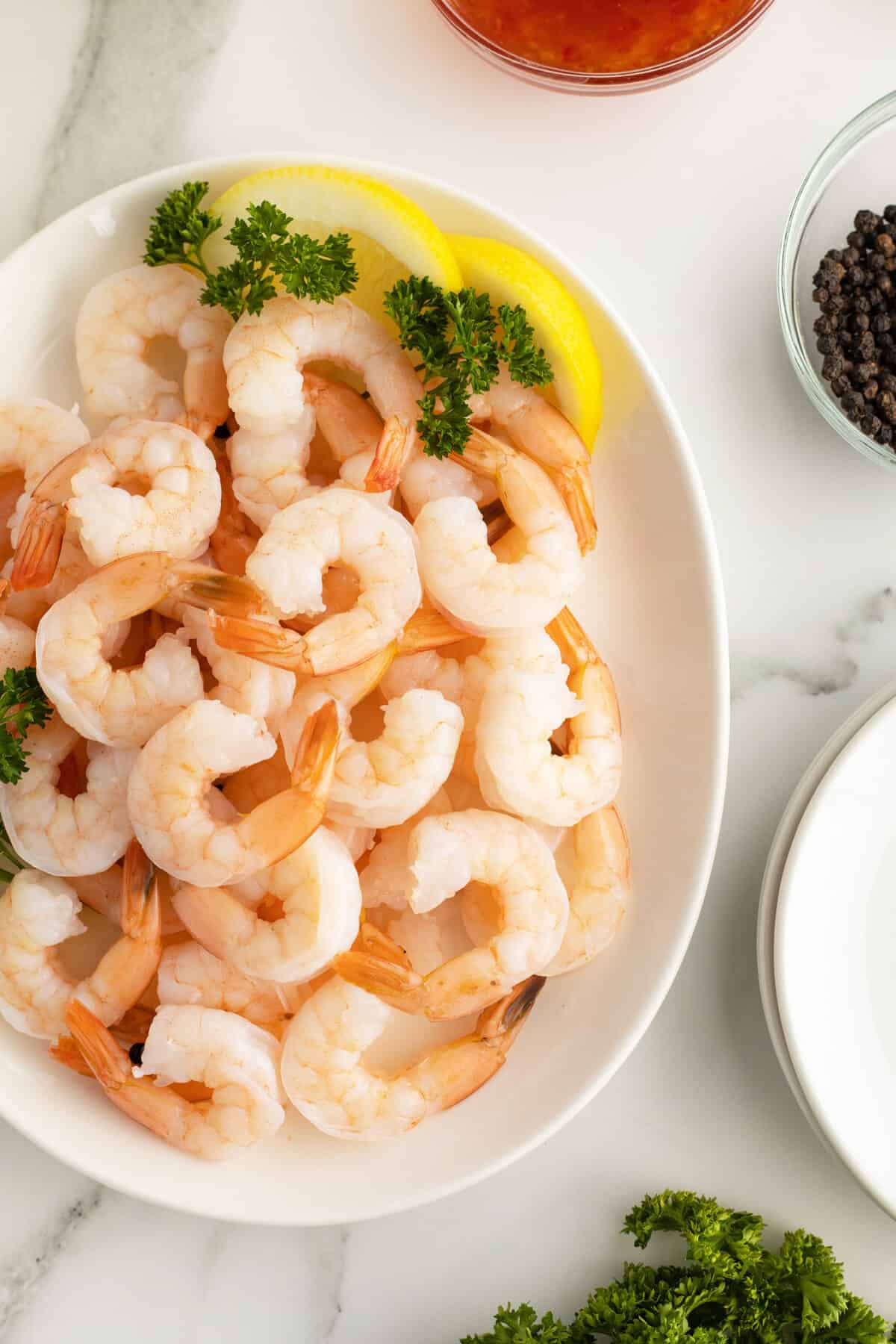 poached shrimp piled on a platter with lemon wedges and parsley