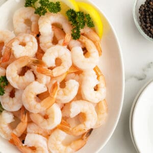 poached shrimp piled on a platter with lemon wedges and parsley