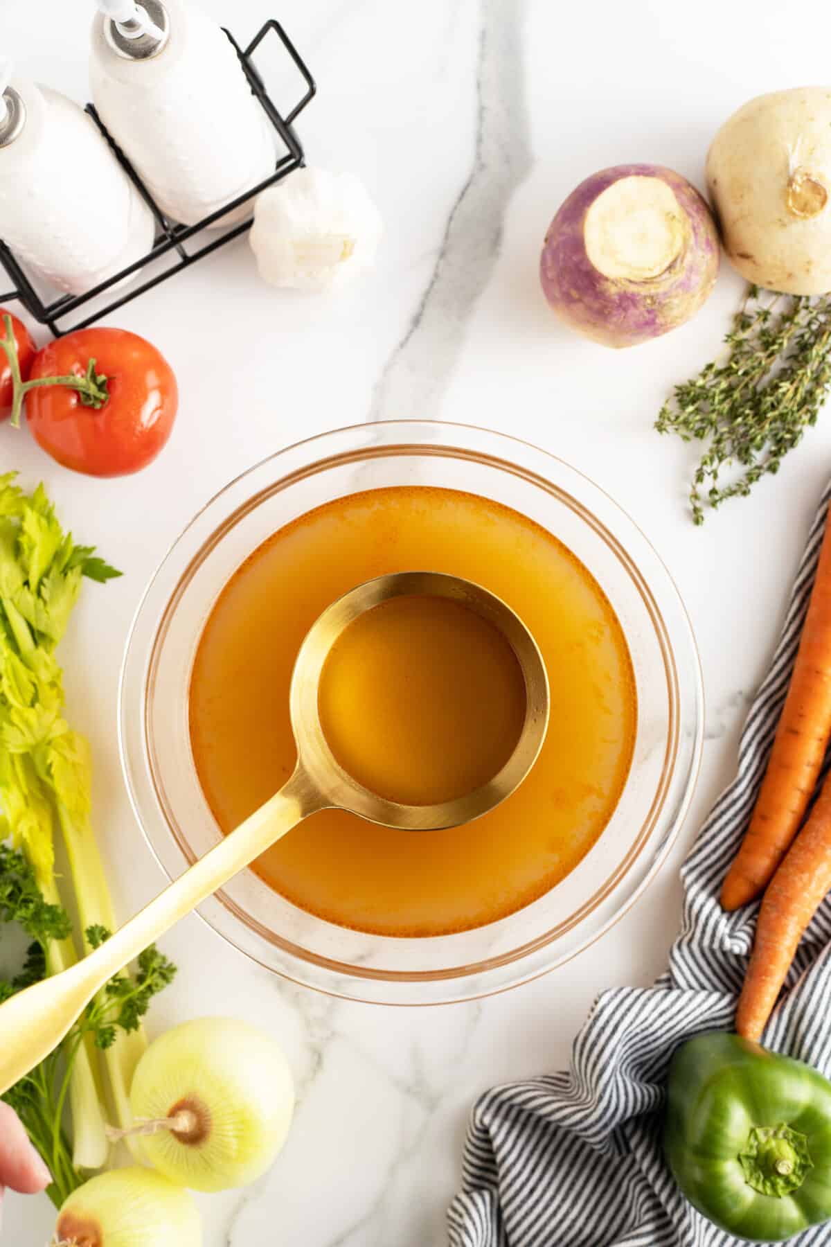 vegetable broth in a clear bowl with a ladle